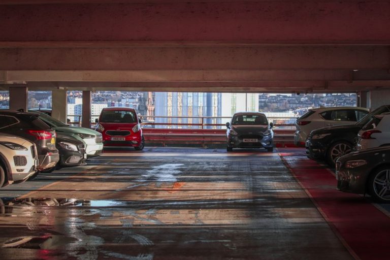 Bărbat care verifică atent o mașină second-hand parcată, cu un carnet de notițe în mână