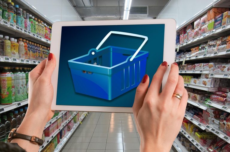 O femeie stă pe canapea cu laptopul în poală și privește gânditoare ecranul